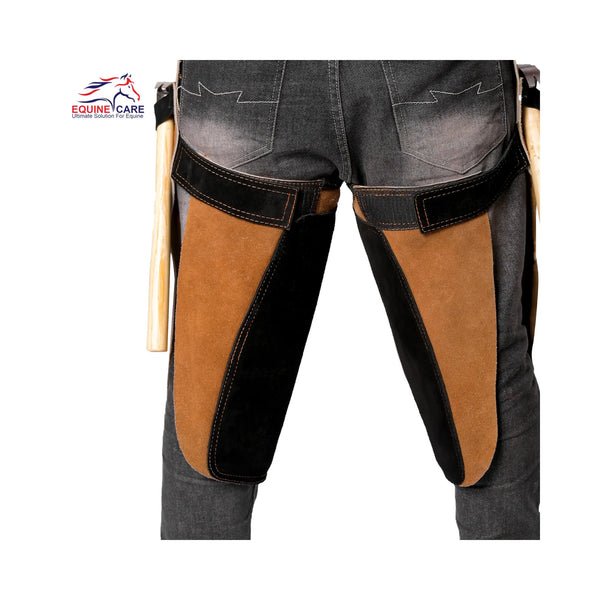 Rear view of 25-inch Premium Elite Farrier Apron worn over jeans, showing tan and black reinforced thigh panels and hammer holders on both sides for professional horse shoeing and farrier work