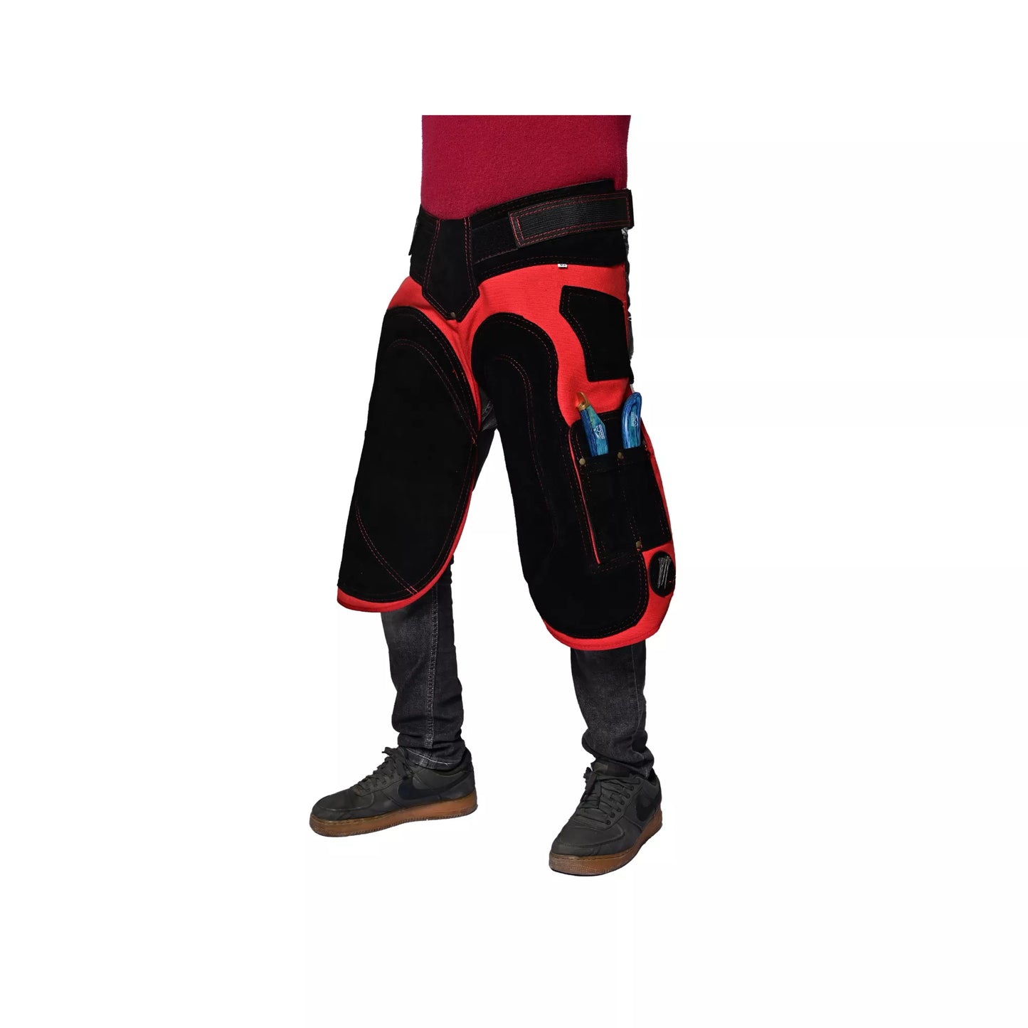 Angled front view of Crimson Shield Farrier Apron worn by a farrier, featuring red and black reinforced thigh protection, adjustable waist belt, and side tool pockets for professional horse shoeing work