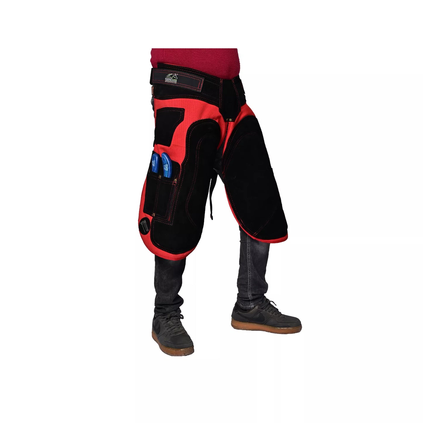Side view of Crimson Shield Farrier Apron worn by a farrier, showing red and black reinforced thigh padding, adjustable waist belt, and integrated tool pockets for professional horse shoeing work