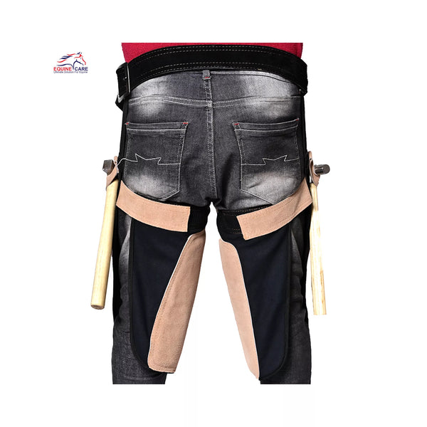 Rear view of Femme Farrier Apron 25-inch worn over jeans, showing black waist support, beige suede thigh panels, and hammer holders on both sides for professional women farriers during horse shoeing work